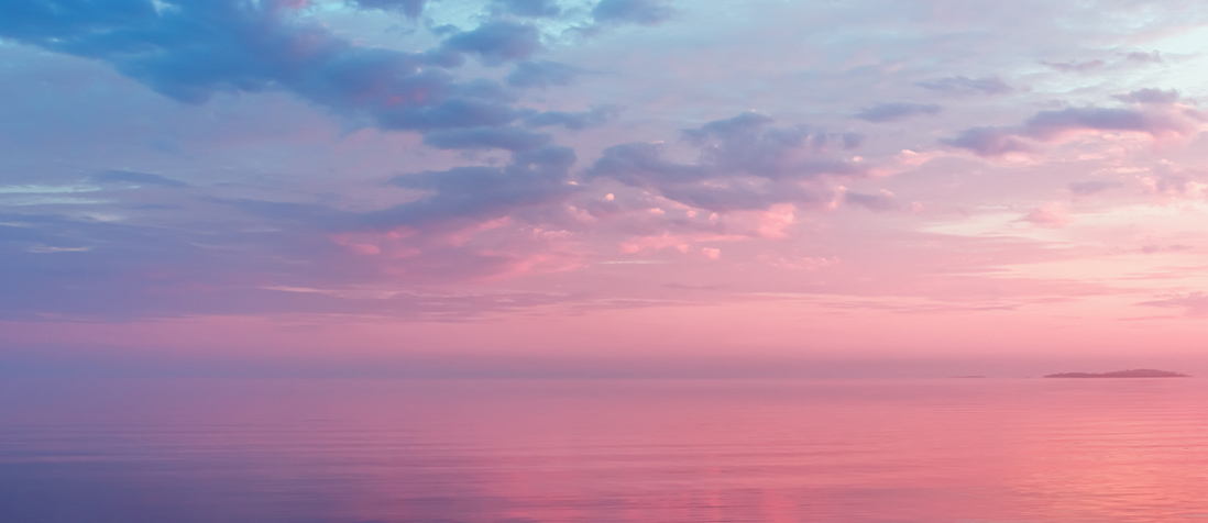 Sunset skyline over the water with a small island in the distance